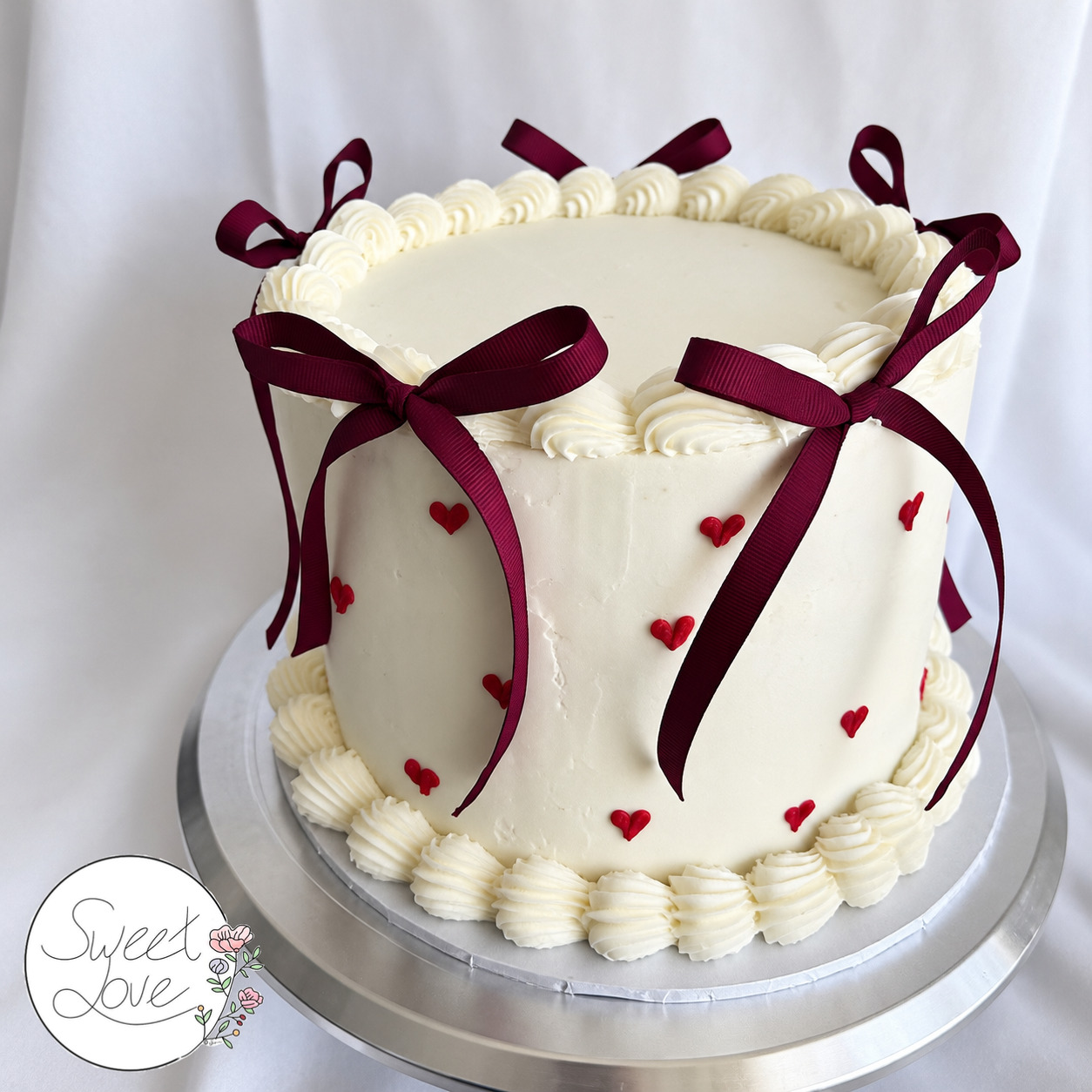 White celebration cake with burgundy bows